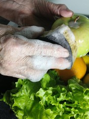 an elderly man washes fruits and vegetables
