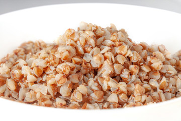 Buckwheat porridge in a white plate close-up.