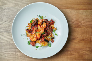 Appetizing seafood salad in sweet and sour sauce in a white plate. Shrimp, octopus, scallops and squid salad