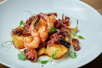 Appetizing seafood salad in sweet and sour sauce in a white plate. Shrimp, octopus, scallops and squid salad