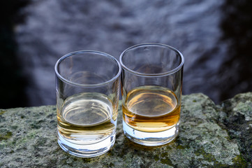Scotch single malts or blended whisky spirits in glasses with water of river Spey on background, Scotland
