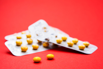 small pills in a blister pack on a red background