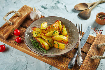 Appetizing fried homemade potato with rosemary and green onions in a ceramic plate on a wooden tray