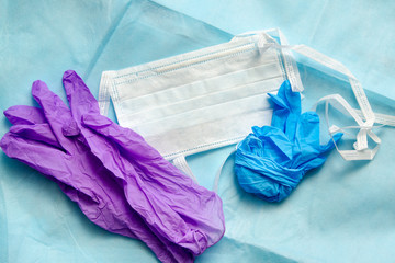 Disposable medical mask and latex gloves on a blue non-woven material. Personal Protection Concept