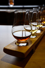 Flight of Scottish whisky, tasting glasses with variety of single malts or blended whiskey spirits on distillery tour in Scotland