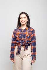 Beautiful young woman portrait. Portrait of a beautiful smiling brunette in a plaid shirt on a white-gray