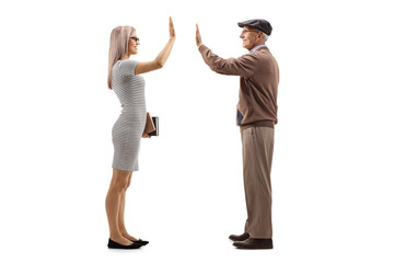 Young woman holding books and gesturing high-five with an elderly man