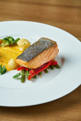 Appetizing grilled salmon steak with a side dish of yellow puree, fresh asparagus, broccoli and cauliflower on a white plate. Healthy and tasty food