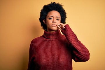 Young beautiful African American afro woman with curly hair wearing casual turtleneck sweater mouth...