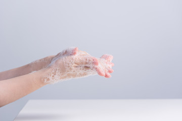 Washing hands. Asian young woman using liquid soap to wash hands, concept of hygiene to protective pandemic coronavirus isolated on gray white background, close up.