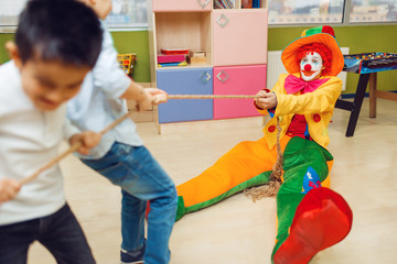 Clown and joyful little boys playing tug of war © Nomad_Soul
