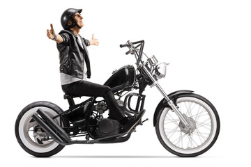 Obraz na płótnie Canvas Elderly man with a leather jacket and helmet riding a chopper motorbike and spreading arms