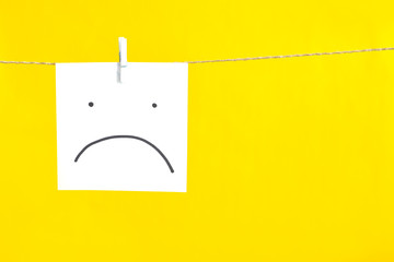  sad smiley on a white sheet hangs on a rope. 