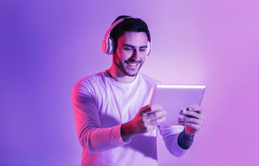 Handsome man with tablet and wireless headphones