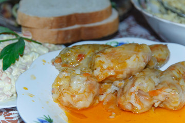   half empty plate with stuffed cabbage leaves with meat, rice and vegetables. meat salad with mayonnaise (olivier) two slices of bread  