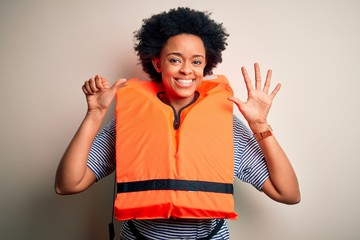 Young African American afro woman with curly hair wearing orange protection lifejacket showing and pointing up with fingers number six while smiling confident and happy.