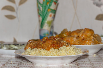 plate on the table with a dish of couscous with goat meat next to a plate of cabbage rolls close-up  