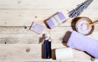 Fototapeta na wymiar Lavender oil, soap with lavender, flavored salt and a bouquet of dry lavender lie on a wooden surface. Body and face care. CPA attributes. Horizontal background