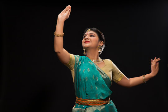 Beautiful kathak dancer performing gracefully over a dark background. 
