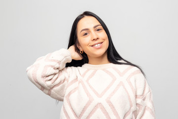 Fototapeta premium Portrait of a young beautiful cute brunette girl in a warm winter sweater on light gray background.