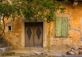 An old wooden door and shuttered window in a derelict building in the historic hill village of...