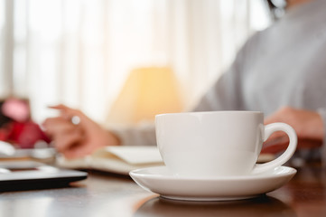 Woman work from home have a coffee cup beside wait epidemic situation to improve soon at home. Coronavirus, covid-19, Work from home (WFH), Social distancing, Quarantine, Prevent infection concept.
