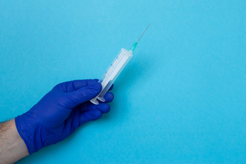 Doctor's hands holding syringe closeup on blue background, coronavirus, illness, infection,...