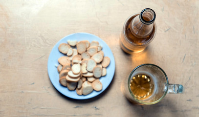 Rusks in a plate, a beer mug, and a bottle with cider on the table top view. Soft focus concept.