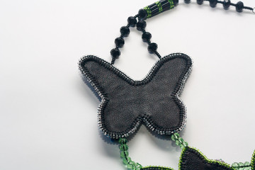Part of beaded necklace in shape of butterfly lying backwards on white background. Female...