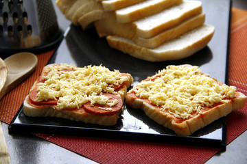 Sliced bread loaf with pizza toppings made of cheese, pepperoni and tomato sauce.