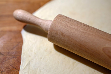 rolled out dough and rolling pin on the wooden board