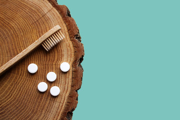 Zero waste flat lay. Bamboo toothbrush, toothpaste tablets on wooden background. Sustainable...