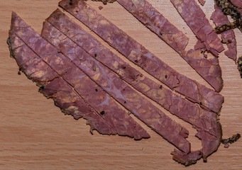 Black peppercorn roast beef. Close-up macro photo of julian chopped roast beef on yellow coffee colored chopping board.