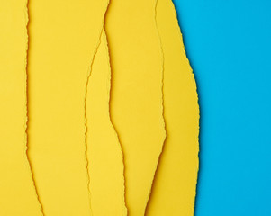 background of layered yellow torn paper with a shadow on a blue background