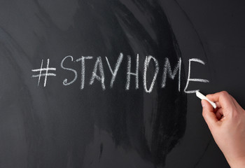 inscription stay home in chalk with a hashtag on a black chalk board