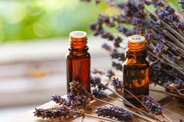 Organic natural essential lavender oil in small brown glass bottles. Dry flowers, green background....