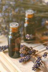 Organic natural essential lavender oil in small brown glass bottles. Dry flowers, wooden background. Concept of natural cosmetics. Faded colors, tonned in yellow. Close up, macro, copy space