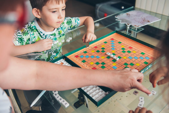  Little boy is playing board. Scrabble game letters. Child set word home.