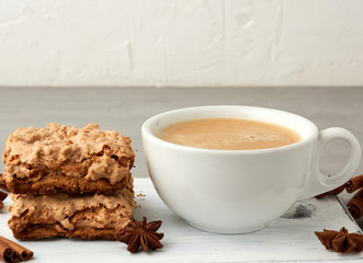 baked Krakow meringue cookies on a wooden board and a white ceramic cup with black coffee