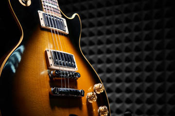 Sunburst electric guitar standing over acoustic foam panel background