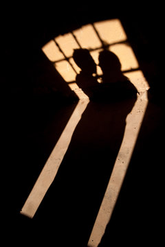 Silhouette of lovers on the window. Shadows from a couple in love on the wall. Silhouette of the bride and groom on the wall.