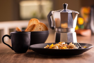 plate with sliced banana with granola, candied fruit and honey, toast and a cup of coffee