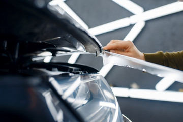 Worker cuts protection film on car hood