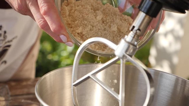 Women putting sugar in a food mixer bowl to bake a cake