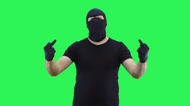 A man in a balaclava shows the middle finger with both hands,green screen background