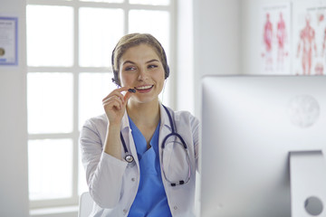 Portrait of a happy smiling young doctor in headset in office