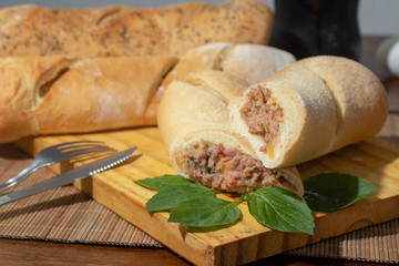 baguette stuffed with sausage pepperoni cut in half on wooden table.