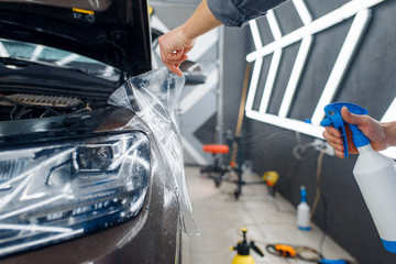 Worker applies car protection film on front fender
