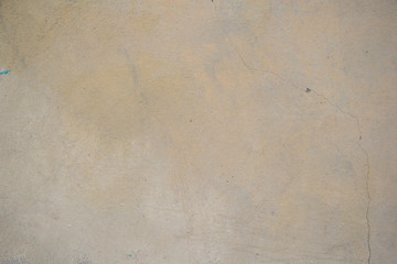 old rough wall of beige color. You can see a small crack. The background is light. The wall is beige with yellow spots