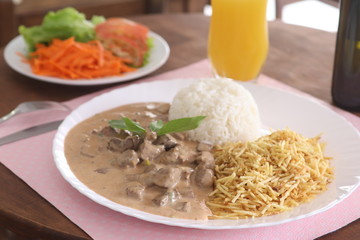 beef stroganoff Beef with white rice and straw potatoes on a white plate
